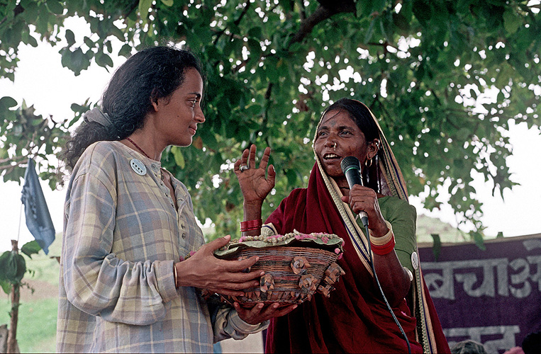 Eine Bäuerin überreicht Arundhati Roy ein Geschenk: Ackerfrüchte