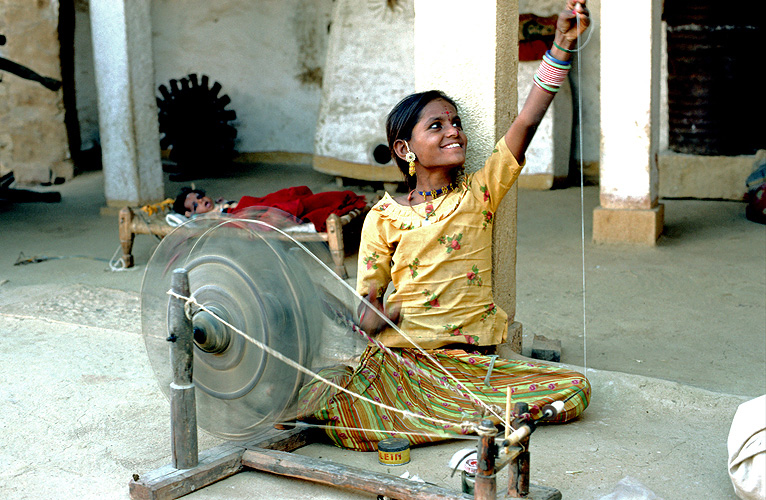 Mädchen am Spinnrad in einem Dorf in Rajasthan